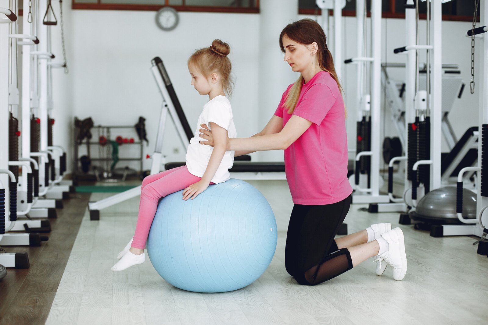 Mother with daughter in a gym. Little girl are engaged in gymnastics